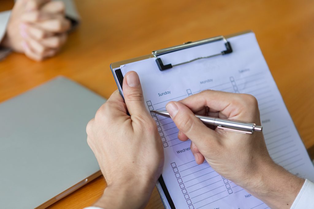Eine Zwischenablage in der Hand eines Managers, der ein Kandidateninterview mit einem Unternehmen schreibt. Zufriedenheitsumfrage bei Dienstleistern